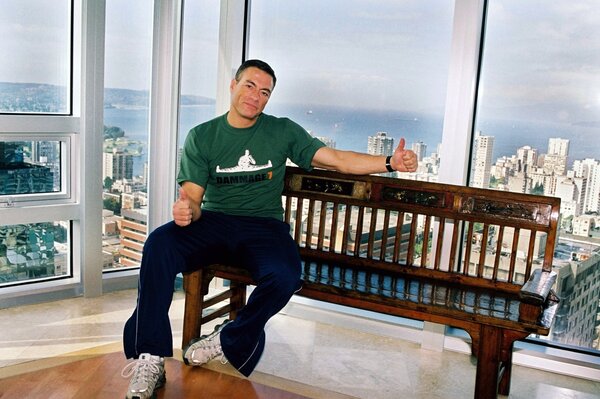 Jean-Claude Van Damme sits on the background of a panorama of the city