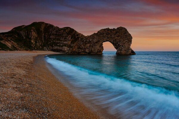 Evening beach, arch in the sea of rock