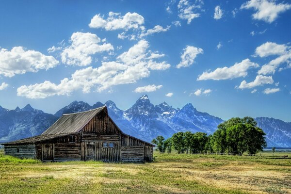 Casa de madera en el campo en el fondo de las montañas