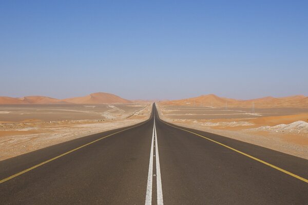 The track is in the desert, sand dunes are visible in the distance