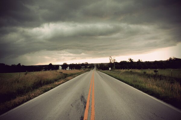 Nuages sombres sur le champ et la route