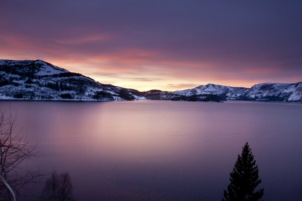 Lila See vor dem Hintergrund der schneebedeckten Berge im Licht des Sonnenuntergangs