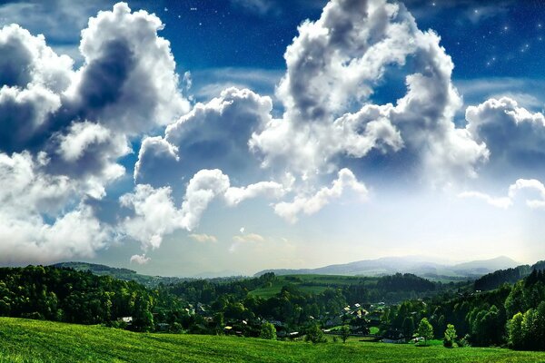 Flauschige Wolken am blauen Himmel über dem grünen Dorf. Landschaft