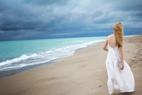 Einsames Mädchen in einem weißen Kleid am Meer