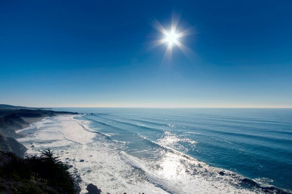 The rays of the sun shine on the ocean, rocks, shore