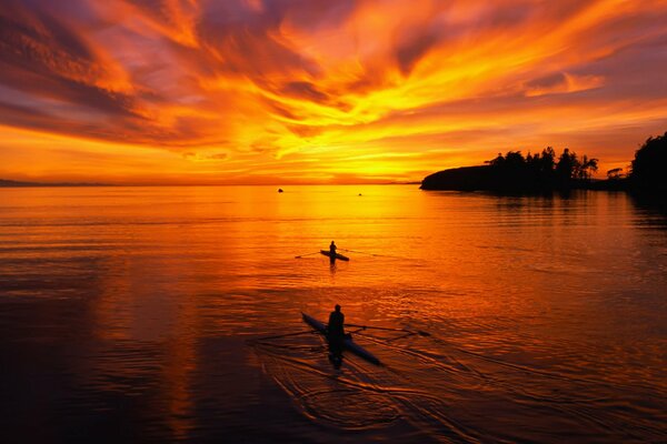 Nageurs sur des bateaux sur fond de coucher de soleil