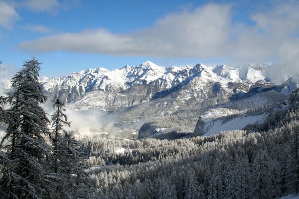 Nuages sur le ciel bleu au-dessus des montagnes enneigées