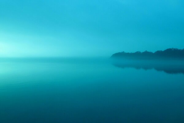 A misty lake reflects the sky