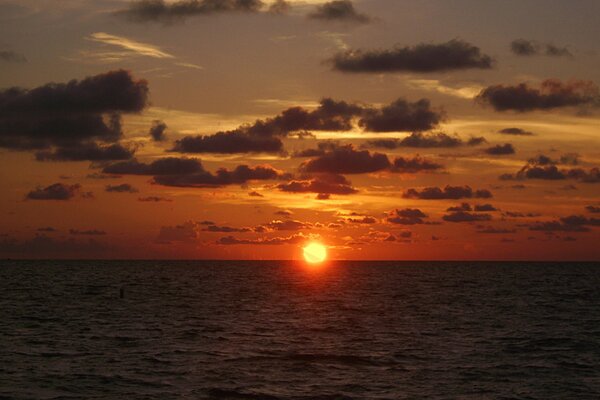 Die Sonne setzt sich ins Meer. Wolken bei Sonnenuntergang