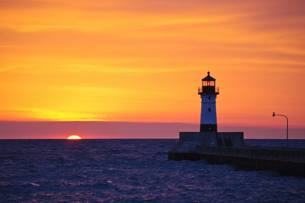 Lighthouse on the background of a sea sunset