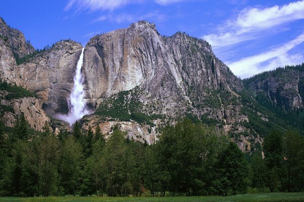 Mountain waterfall against a bright blue sky