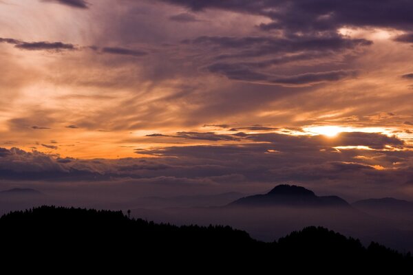 Hermosa puesta de sol detrás de las nubes y las montañas