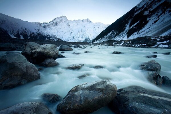 Fließender Fluss vor dem Hintergrund der schneebedeckten Berge