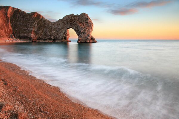 Plage et rocher noyé dans la mer au coucher du soleil