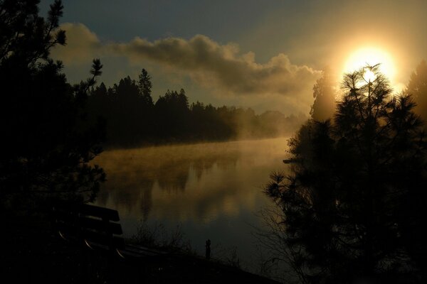 Banc près de la rivière et beau ciel avec le soleil