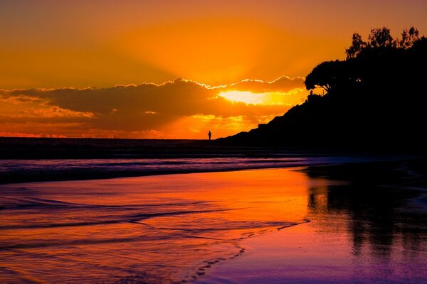 Puesta de sol en una playa seria con un hombre en la distancia