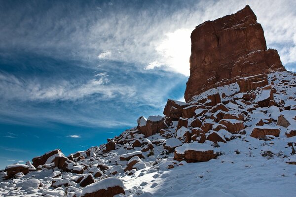 Felsen auf einem schneebedeckten Gipfel auf einem blauen Himmelshintergrund