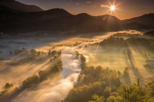Through the misty valley, the sunlight peeps out, its ray shines on the mountains and the river