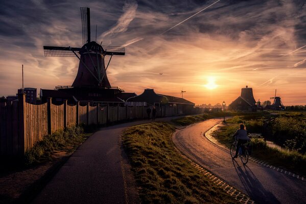 A man rides a bicycle near a mill