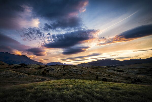 The sky at dawn over a green hill