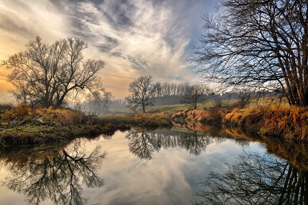 Autumn wallpaper with reflection of trees and sky in the river