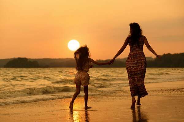 Mom and daughter walking on the beach