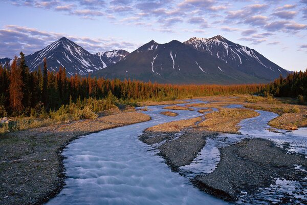 El curso del río cerca de las montañas al atardecer