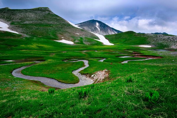 Mountain panorama with a winding river and green grass