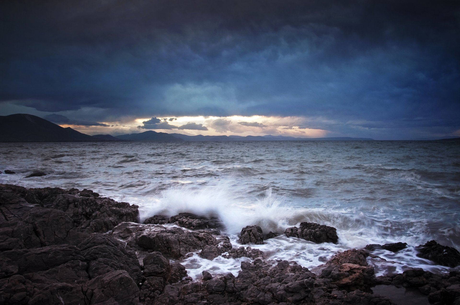 mer vagues éclaboussures pierres montagnes nuages