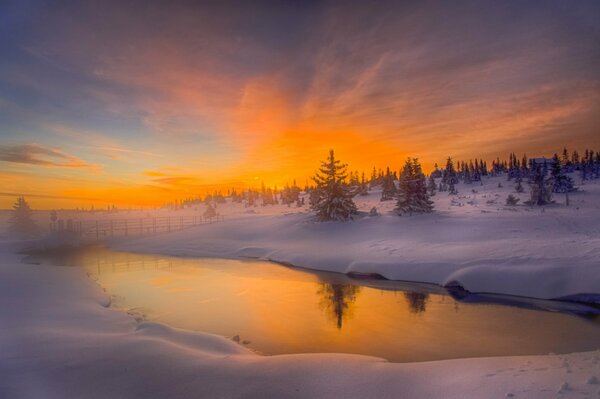 Amanecer naranja en el río de invierno