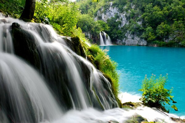 Ein Bergfall, der in einen blauen See mündet