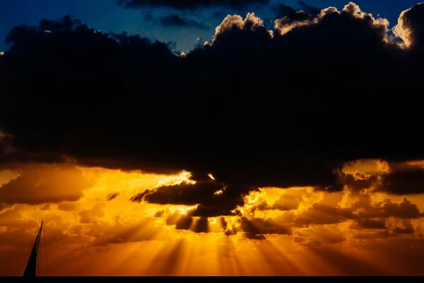 The sunset rays of the sun break through from behind the clouds