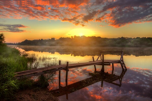 Morgendlicher Fluss mit Brücke im Nebel