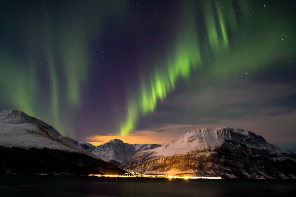 Northern lights in the sky. Snowy Mountains