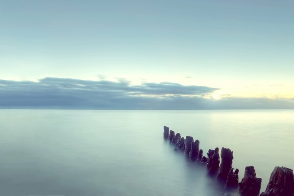 Puesta de sol junto al mar y bolardos en el agua