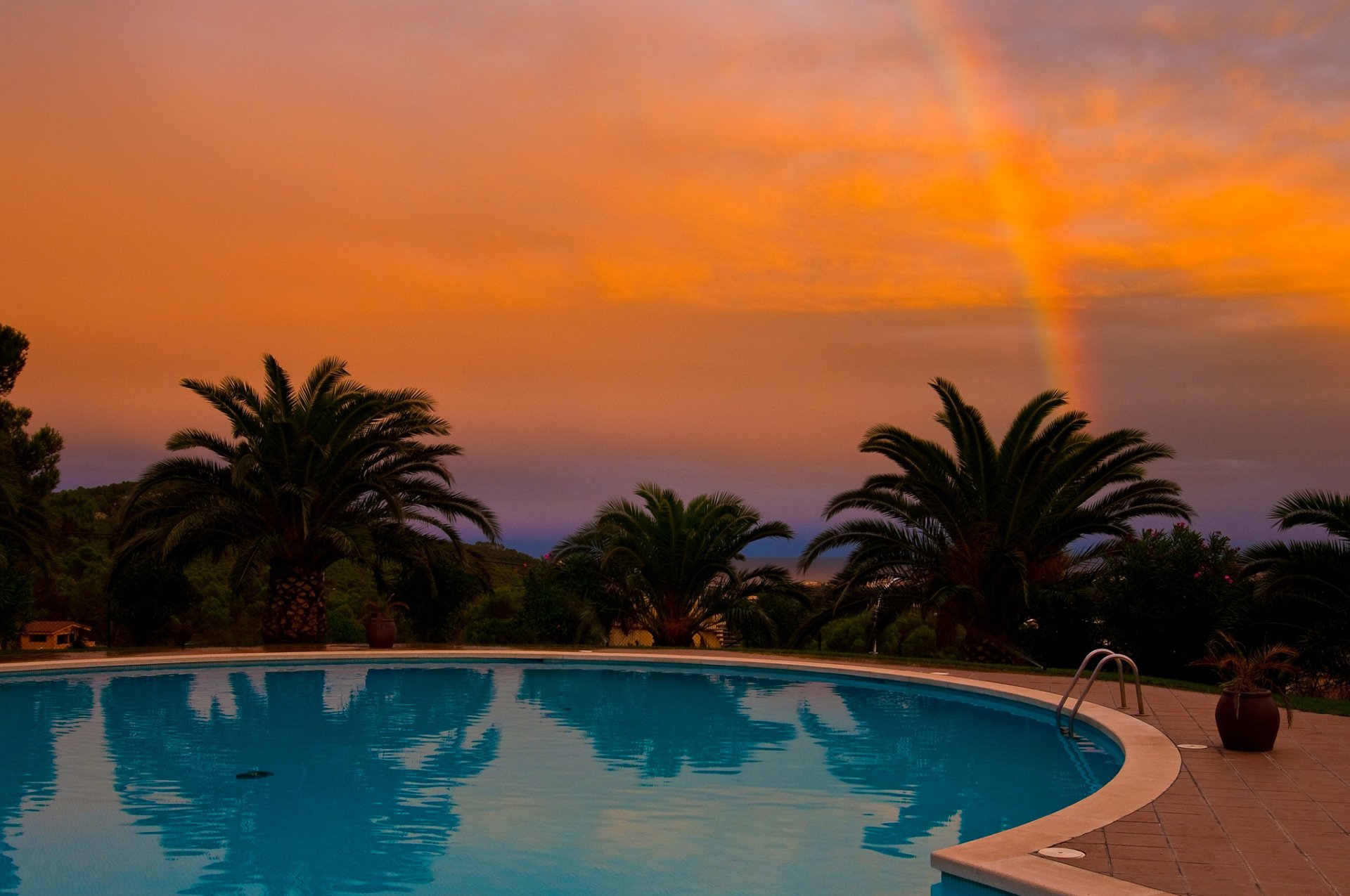 palmeras puesta de sol arco iris piscina