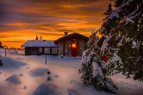 Il tramonto è bello. Il paesaggio include la casa neve cielo che sono vestiti con colori invernali. la natura brucia deliziosamente trasformando la neve bianca in un estensione del cielo arancione