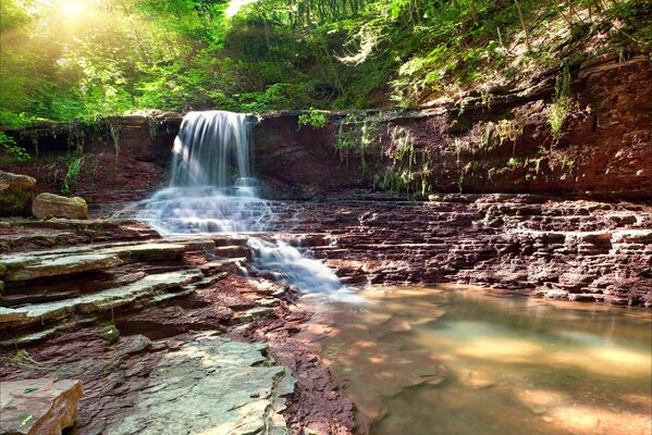 Stein Wasserfall im Wald in der Sonne