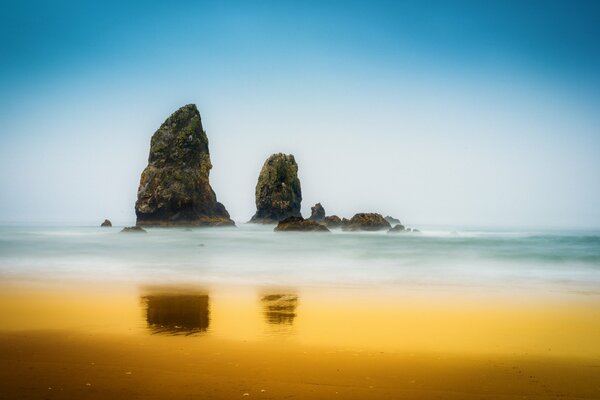 Hermosa naturaleza rocas en medio del mar y arena dorada