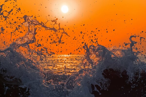 Spruzzi di mare del mare sullo sfondo di un tramonto luminoso