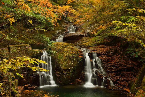 Waterfall among rocks and autumn trees