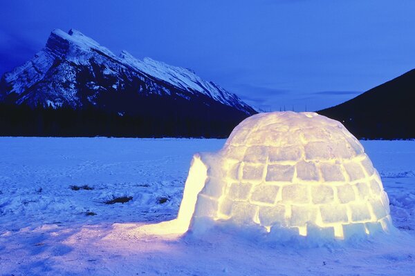 Ice yurt with light on snow at night