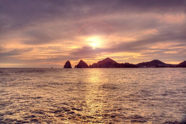 Sunset on the sea. Rocks in the distance