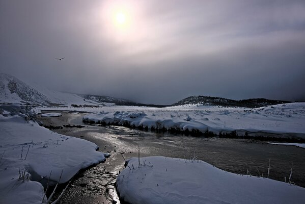 Río de invierno con nieve en la orilla