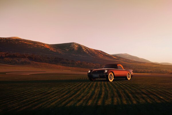 On the highway, against the background of the mountains, a red car is driving