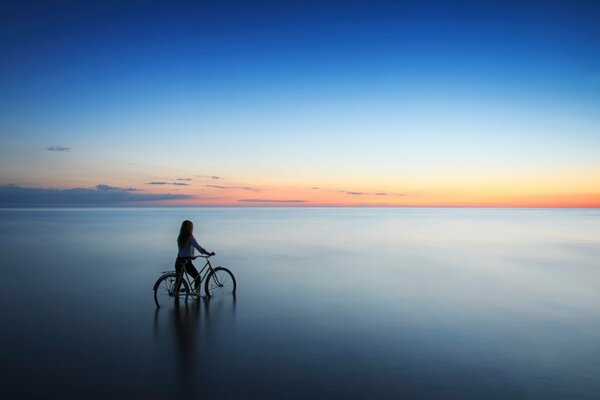 Una chica con una bicicleta se mete en el agua