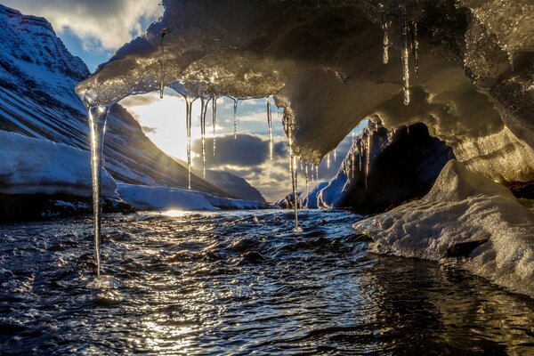 Eiszapfen hängen über dem Fluss vor dem Hintergrund der Sonne