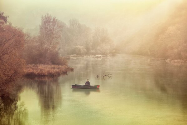 A lonely fisherman on the river in the fog