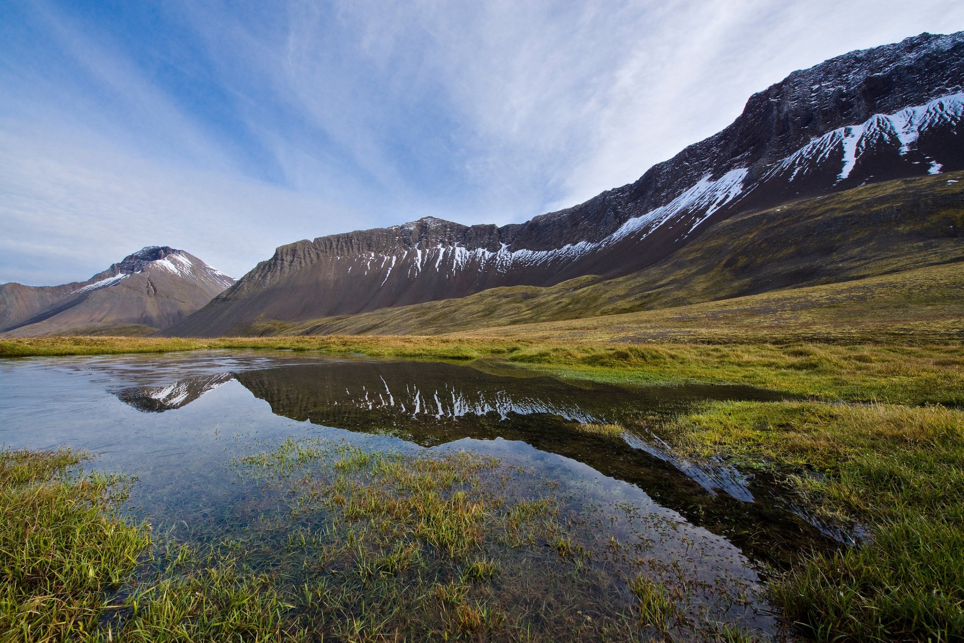 islandia dolina góry trawa jezioro niebo chmury odbicie