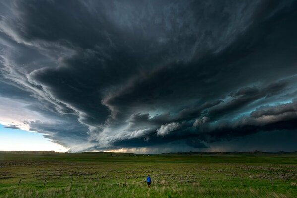 Un hombre en un campo bajo un cielo oscuro y tormentoso